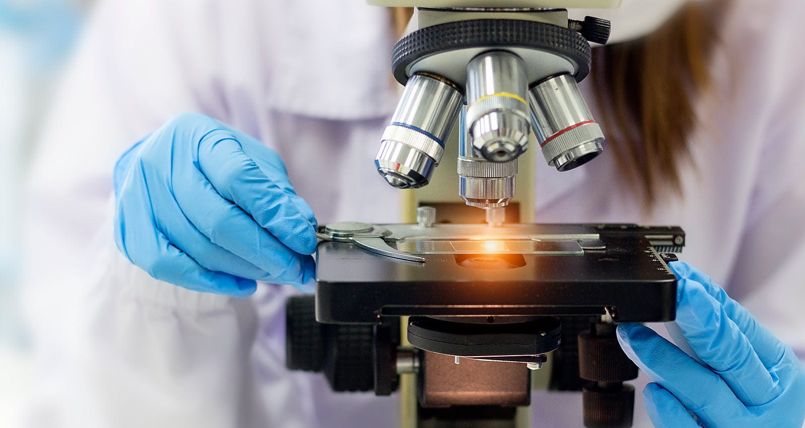 A clinical researcher looks through a microscope in a laboratory